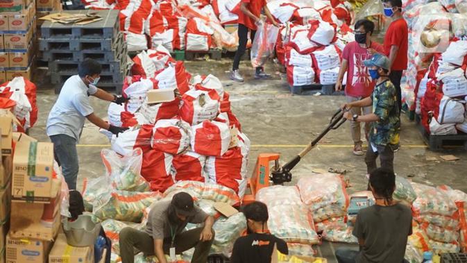 Pekerja memindahkan paket bansos di Gudang Food Station Cipinang, Jakarta, Rabu (22/4/2020). Pemerintah menyalurkan paket bansos sebesar Rp 600 ribu per bulan selama tiga bulan untuk mencegah warga mudik dan meningkatkan daya beli selama masa pandemi COVID-19. (Liputan6.com/Immanuel Antonius)