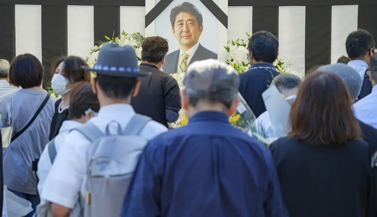 Orang-orang meninggalkan bunga dan memberi penghormatan kepada mantan Perdana Menteri Jepang Shinzo Abe menjelang pemakaman kenegaraannya di Tokyo, Selasa, 27 September 2022. Abe meninggal usai ditembak Tetsuya Yamagami saat menyampaikan pidato di sekitar Stasiun Nara pada awal Juli lalu. (Nicolas Datiche/Pool Photo via AP)