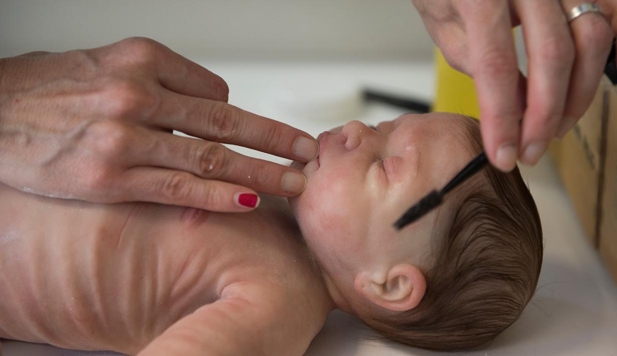 Pekerja menyisir rambut boneka bayi silikon yang mirip manusia di Clon Factory, Kota Leioa, Spanyol Basque, Selasa (20/6). Boneka bayi itu dibuat dari bahan platinum silikon dan bahan-bahan yang serupa digunakan dalam bedah kosmetik. (ANDER GILLENEA/AFP)