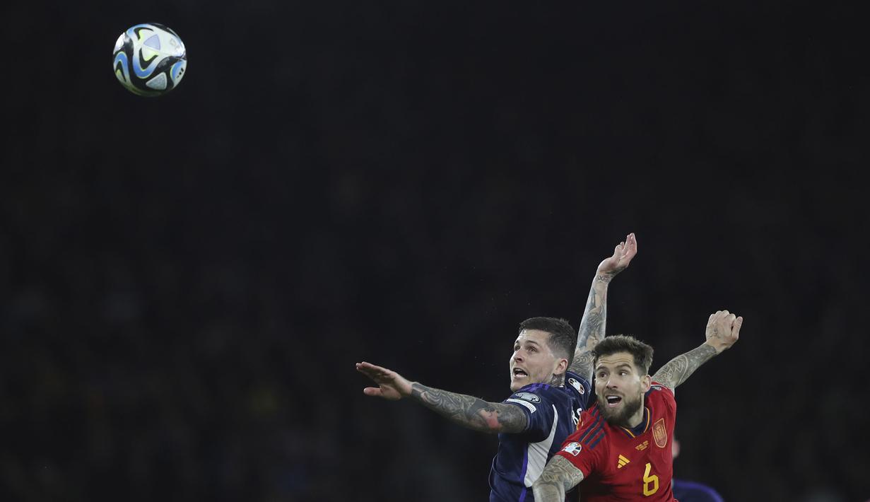 Pemain Skotlandia, Lyndon Dykes (kiri) berebut bola dengan pemain Spanyol, Inigo Martinez during the Euro 2024 group A qualifying soccer match between Scotland and Spain at the Hampden Park stadium in Glasgow, Scotland, Tuesday, March 28, 2023. (AP Photo/Scott Heppell)