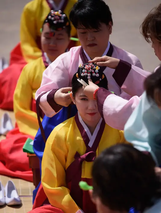 Seorang wanita muda melakukan ritual penyematan ornamen kepala selama upacara “Coming of Age” di Namsan Hanok Village, Seoul, Senin (20/5/2019). Di Korea Selatan, Coming of Age Day atau hari kedewasaan dirayakan secara nasional setiap tahun pada hari Senin ketiga di bulan Mei. (Ed JONES/AFP)