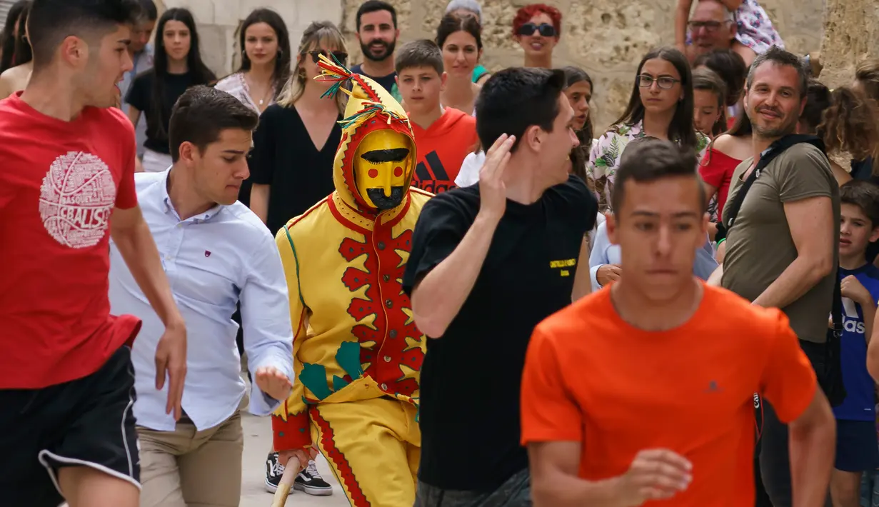 Pria berkostum setan mengejar kerumunan orang pada tradisi 'setan melompati bayi' atau disebut juga El Salto del Colacho di desa Castrillo de Murcia, bagian utara Spanyol, 23 Juni 2019. Festival dimulai ketika kerumunan orang termasuk para orang tua dari bayi-bayi sudah berkumpul. (CESAR MANSO/AFP)