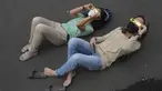 Orang-orang berbaring di tanah saat mereka menggunakan kacamata khusus untuk menyaksikan gerhana matahari hibrida di Jakarta, Kamis (20/4/2023). (AP Photo/Tatan Syuflana)