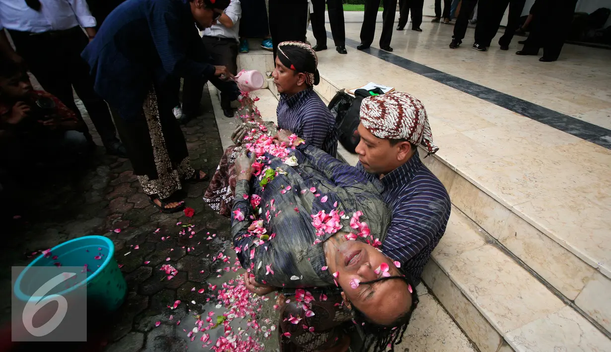 Soerang pengunjukrasa saat dimandikan kembang usai melakukan aksi teatrikal  manusia semen di depan Gedung DPRD DIY, (29/2). Mereka menuntut keseimbangan dalam fungsi dan kepemilikan ruang dengan masyarakat. (Liputan6.com/Boy Harjanto)