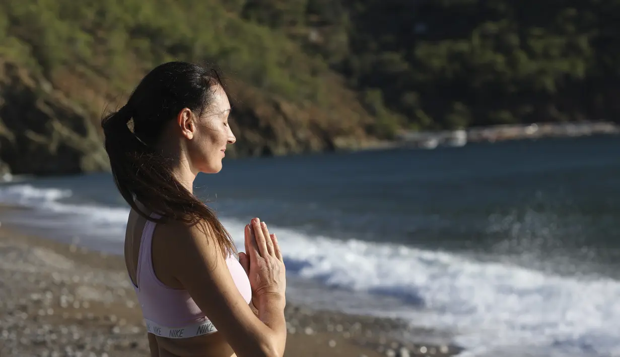 Seorang wanita berlatih yoga di pantai di Adrasan, barat Antalya, Turki (24/9/2021). Orang-orang menikmati cuaca hangat di wilayah Mediterania saat salju pertama menyelimuti pegunungan tinggi di timur laut Turki. (AP Photo/Burhan Ozbilici)