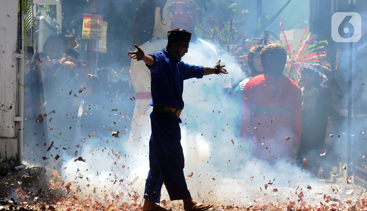 Warga saat melakukan aksi memegang petasan besar yang dibakar pada kegiatan pawai jelang Ramadan di kawasan Pondok Cabe Ilir, Tangerang Selatan, Banten, Minggu (27/3/2022). Kegiatan yang diselenggarakan Sanggar Seni Rumah Baba ini diikuti puluhan warga. (merdeka.com/Arie Basuki)