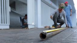 Seorang pekerja mengukur pipa untuk perbaikan pintu stadion yang rusak di Stadion Utama Gelora Bung Karno, Kamis (22/2/2018). Empat pintu stadion yang mengalami kerusakan adalah pintu bernomor 5B, 7B, 9, dan 10. (Bola.com/Nick Hanoatubun)