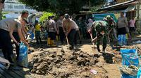 Personil TNI dan Polri, Senin (30/1/2023), membantu warga membersihkan material sisa banjir dan longsor di Manado.