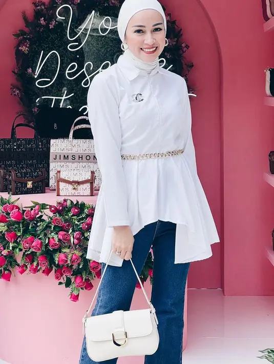 Tunik asimetris putih tampil stylish dan simple dengan jeans. Aryani memadukannya dnegan belt, hijab turban, dan anting hoop. [@aryanifitriana24]