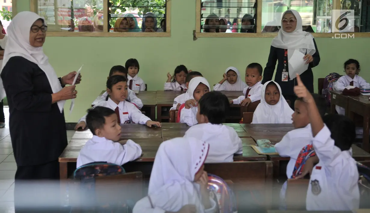 Dua guru mendampingi murid yang mengikuti aktivitas belajar mengajar di SDN Jatinegara Kaum 15 Pagi, Jakarta, Senin (15/7/2019). Sebanyak 32 anak menjadi murid baru SDN tersebut pada hari pertama masuk sekolah tahun ajaran 2019/2020. (merdeka.com/Iqbal S Nugroho)