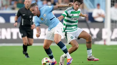 Gelandang Manchester City Kalvin Phillips berebut bola dengan gelandang Glasgow Celtic, Matt O'Riley dalam pertandingan uji coba di Stadion Kenan Momorial, Amerika Serikat, Rabu (24/7/2024) pagi WIB. (GRANT HALVERSON / GETTY IMAGES NORTH AMERICA / Getty Images via AFP)