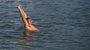 Seorang pria meregangkan tubuh di pantai Arpoador selama gelombang panas di Rio de Janeiro, Brasil, pada hari libur kota Saint Sebastian, Kamis (20/1/2022). (AP Photo/Bruna Prado)