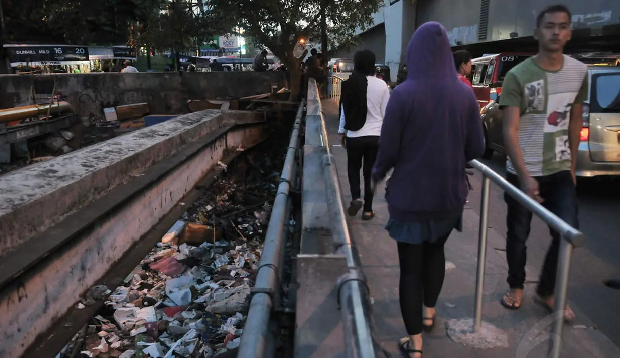 Tanpa memperdulikan bau sampah yang mulai menyengat, beberapa warga tetap melintasi jembatan kali Roxy, Jakarta, (9/8/2014). (Liputan6.com/Johan Tallo)