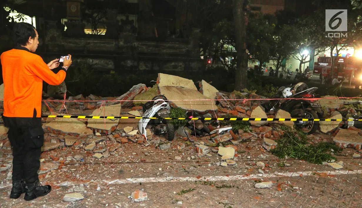 Warga mengabadikan kendaraan bermotor yang tertimbun reruntuhan bangunan parkir bertingkat akibat gempa di Mal Galeria, Ngurah Rai, Bali, Minggu malam (5/8). Gempa di Lombok Utara, NTB mengakibatkan bangunan parkir rusak. (Liputan6.com/Johan Tallo)