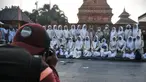 Fotografer saat memotret peziarah dengan latar belakang Menara Kudus, Kauman, Kabupaten Kudus, Jawa Tengah, Rabu (30/3/2022). Musim ziarah membawa berkah tersendiri bagi para fotografer keliling di kawasan Makam Sunan Kudus. (merdeka.com/Iqbal S. Nugroho)