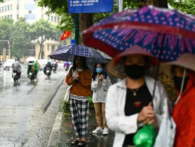 Para penumpang menunggu di halte bus selama hujan lebat di Hanoi (14/10/2020). Badai tropis Nangka menghantam Vietnam tengah-utara yang mengakibatkan bencana alam, terutama hujan lebat dan banjir, telah menyebabkan 28 orang tewas dan 12 lainnya hilang. (AFP Photo/Manan Vatsyayana)