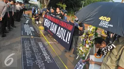 Spanduk berisi tuntutan penuntasan kasus pelanggaran HAM digelar di depan Istana Negara, Jakarta, Kamis (2/7/15). Dalam aksinya mereka meminta kepada Jokowi untuk menuntaskan kasus pembunuhan Jopi. (Liputan6.com/Herman Zakharia)