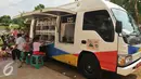 Sejumlah anak membaca buku di mobil perpustakaan keliling di halaman Rusun Cipinang Besar Selatan, Jakarta, Rabu (27/4). Pemprov DKI Jakarta melengkapi fasilitas rusun tersebut berupa perpustakaan dan taman bermain anak. (Liputan6.com/Gempur M Surya)