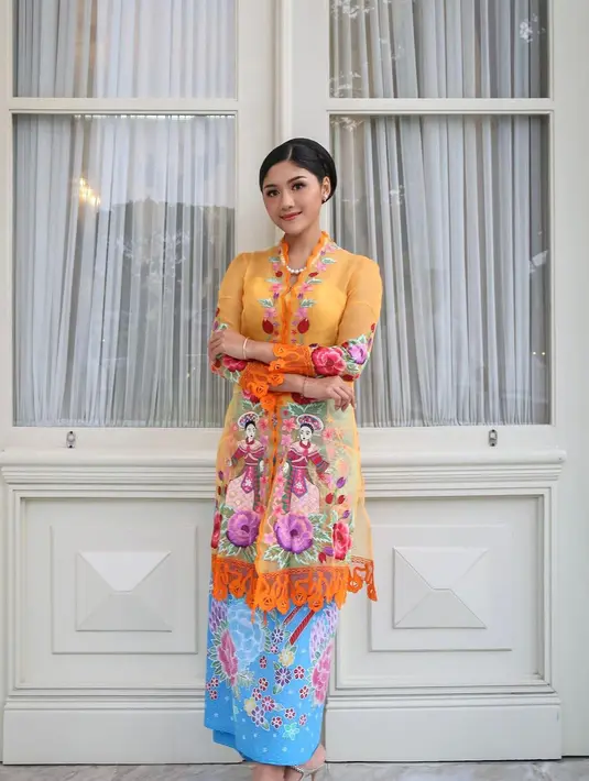 Erina Gudono tampil anggun dalam balutan kebaya encim berwarna oranye motif penari dipadu kain batik Betawi berwarna sky blue. Penampilannya dipermanis dengan anting dan kalung mutiara. [Instagram/erinagudono]