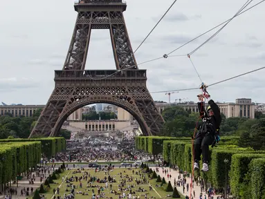 Seorang wanita meluncur dengan seutas tali saat melakukan flying fox dari Menara Eiffel, Paris, 5 Juni 2017. Kesempatan ini dibuka untuk umum jelang turnamen tenis French Open agar dapat merasakan bagaimana kecepatan bola tenis (AP Photo/Kamil Zihnioglu)