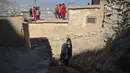 Seorang petugas kesehatan berjalan ketika anak-anak melihatnya selama kampanye vaksinasi di Kabul, Afghanistan pada 8 November 2021. Vaksinasi tersebut merupakan yang pertama sejak Taliban berkuasa di Afghanistan. (WAKIL KOHSAR / AFP)