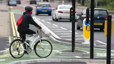 Seorang wanita mengendarai sepeda di jalur sepeda persimpangan CYCLOPS (Cycle Optimized Protected Signals) di wilayah selatan Manchester, Inggris (9/10/2020). Persimpangan CYCLOPS diluncurkan dengan desain unik yang memisahkan pejalan kaki dan pesepeda dari lalu lintas. (Xinhua/Jon Super)