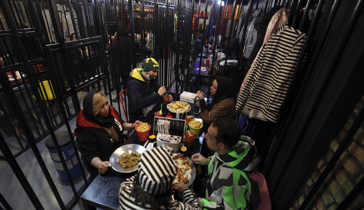 Pengunjung makan malam di restoran berkonsep penjara "Sel 16" di Teheran, 4 Februari 2022. Sebagian hasil bisnis digunakan untuk membebaskan mereka yang mendekam di penjara karena utang yang belum dibayar dimana lebih dari 11.000 warga Iran dipenjara karena gagal membayar utang. (ATTA KENARE/AFP)