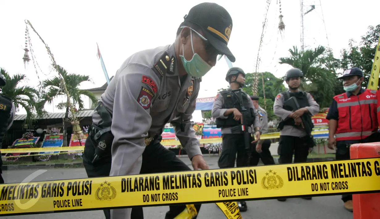 Petugas memasang garis polisi di lokasi bom bunuh diri di Mapolresta Solo, Jawa Tengah, Selasa (5/7). Garis polisi tersebut dipasang mulai dari sisi barat jalan Adi Sucipto menuju sisi timur Jalan KS Tubun. (Liputan6.com/Boy Harjanto)