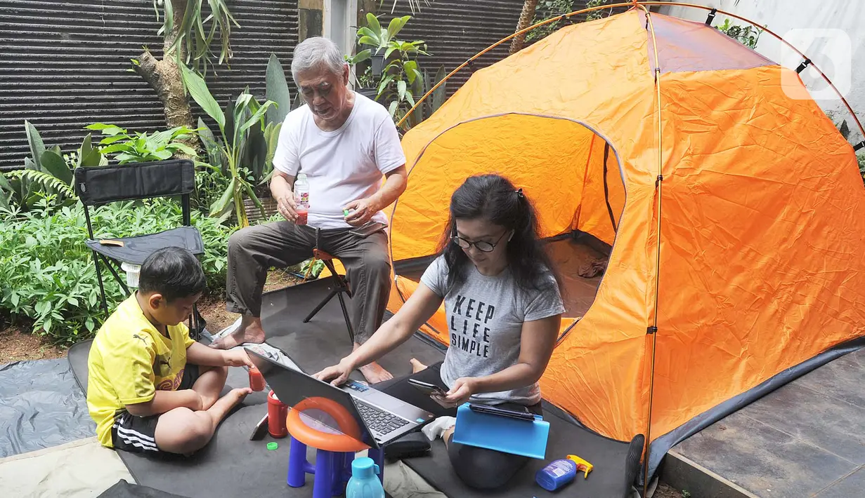 Warga bekerja menggunakan laptop di halaman rumahnya di kawasan Cinere, Depok, Senin (23/3/2020). Imbauan pemerintah untuk bekerja dari rumah atau work from home untuk mencegah penularan virus corona, dimanfaatkan warga dengan beragam aktivitas. (merdeka.com/Arie Basuki)