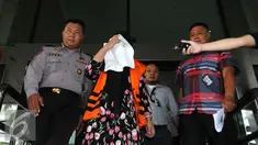 Komisaris CV Timur Alam Raya, Sri Astuti menutupi wajah usai menjalani pemeriksaan di KPK, Jakarta, Senin (22/8). Sri Astuti diduga melakukan penyuapan terkait pengadaan pupuk urea di PT Berdikari tahun anggaran 2010-2012. (Liputan6.com/Helmi Afandi)