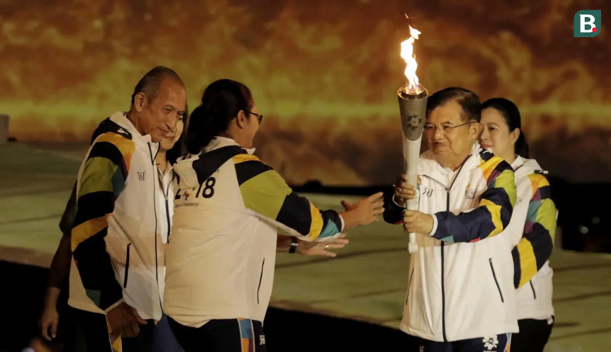 Wapres RI, Jusuf Kalla, menyerahkan api obor kepada pebulutangkis asal Yogyakarta, Kinarsih, saat prosesi kirab obor di Candi Prambanan, Rabu (18/7/2018). Api obor Asian Games tersebut akan dibawa mengelilingi 18 provinsi. (Bola.com/M Iqbal Ichsan)