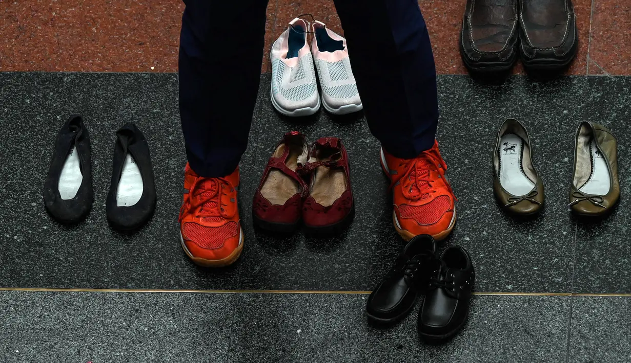 Seorang staf medis berdiri di antara sepasang sepatu, bagian dari instalasi seni dengan 321 pasang sepatu yang menandakan kematian akibat merokok, dalam rangka memperingati Hari Tanpa Tembakau Sedunia di Pusat Paru Filipina, Quezon City, pinggiran kota Manila, Filipina, Selasa (31/5/2022). (JAM STA ROSA/AFP)