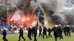 Petugas kepolisian berusaha menenangkan suporter yang mengamuk saat pertandingan antara Hamburg SV melawan VfL Borussia Moenchengladbach di Volksparkstadion, Sabtu (12/5/2018). Hamburg SV terdegradasi dari Bundesliga Jerman. (AP/Michael Sohn)