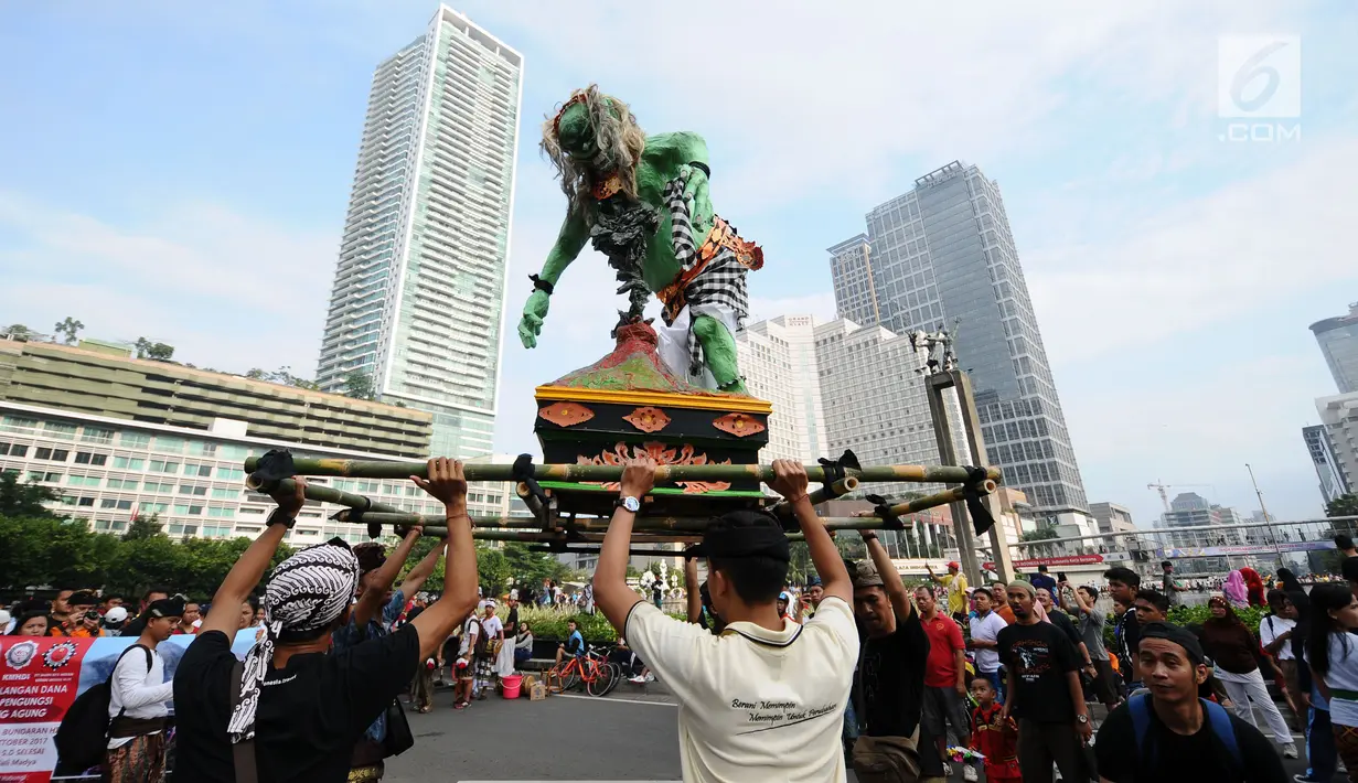 Aktivis Perhimpunan Pemuda Hindu Indonesia menampilkan tarian ogoh-ogoh saat aksi penggalangan dana untuk pengungsi Gunung Agung saat Hari Bebas Kendaraan di Kawasan Bundaran HI Jakarta, Minggu (1/10). (Liputan6.com/Helmi Fithriansyah)