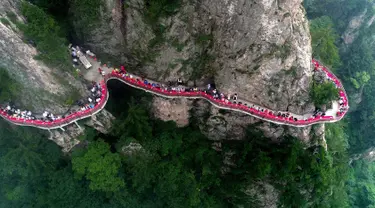 Sebuah acara perjamuan yang diadakan di sepanjang tepi tebing di Laojun Mountain provinsi Henan, bagian tengah China. Wisatawan menikmati berbagai suguhan makanan di jalanan selebar enam kaki yang menempel pada tebing setinggi 2.000 meter. (AFP)