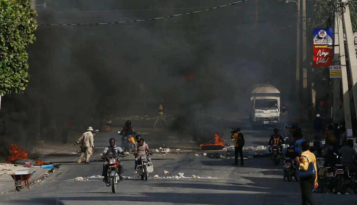 Polisi membersihkan barikade dari ban yang dibakar oleh pengunjuk rasa yang marah dengan meningkatnya kekerasan di lingkungan Lalue, Port-au-Prince, Haiti, Rabu (14/7/2021). Presiden Haiti Jovenel Moise dibunuh pada 7 Juli. (AP Photo/Fernando Llano)