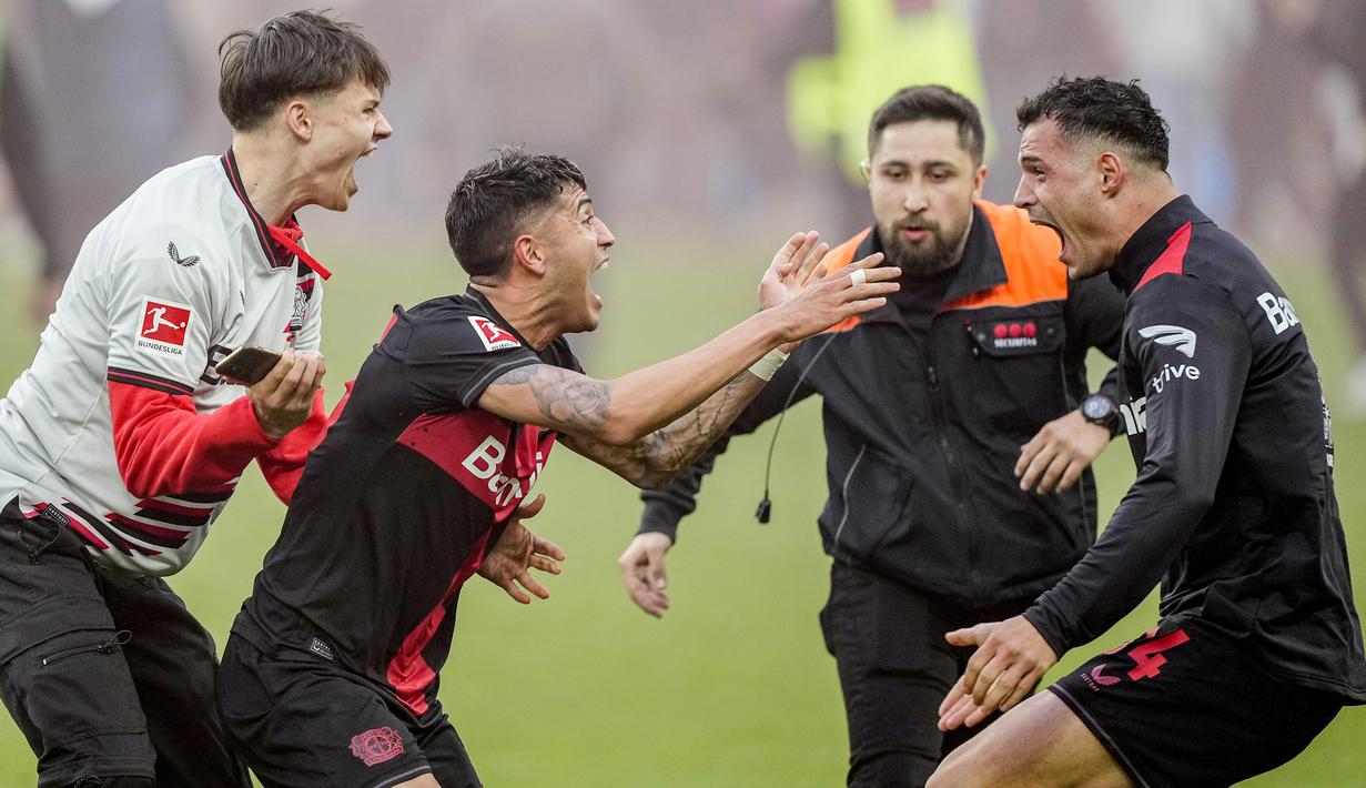 Seorang suporter ikut melakukan selebrasi bersama para pemain Bayer Leverkusen saat memastikan gelar juara Liga Jerman 2023/2024 setelah mengalahkan Werder Bremen di BayArena, Leverkusen, Jerman, Senin (15/04/2024) WIB. (AP Photo/Martin Meissner)