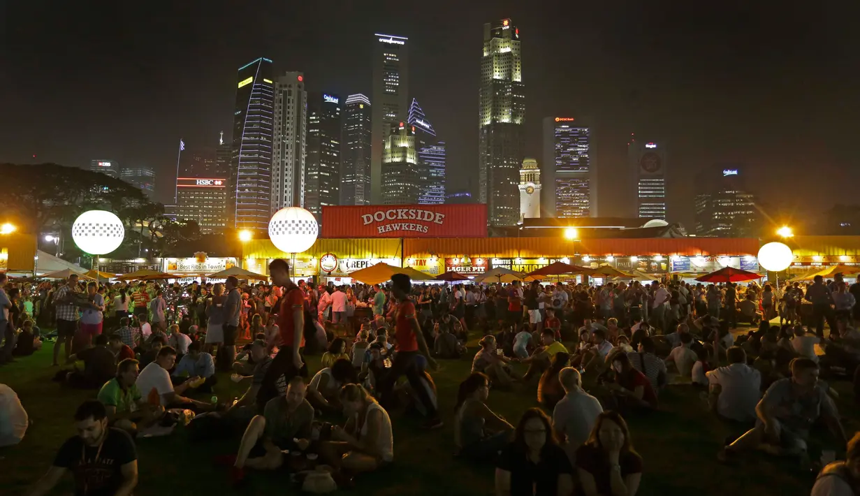 Sejumlah pendukung bersantai di rumput menunggu ajang sesi latihan Grand Prix Singapura F1 (18/9/2015). Kabut asap yang menyelimuti sirkuit tak menyurutkan pembalap untuk tetap melakukan pemanasan. (Singapore Grand Prix /Reuters)