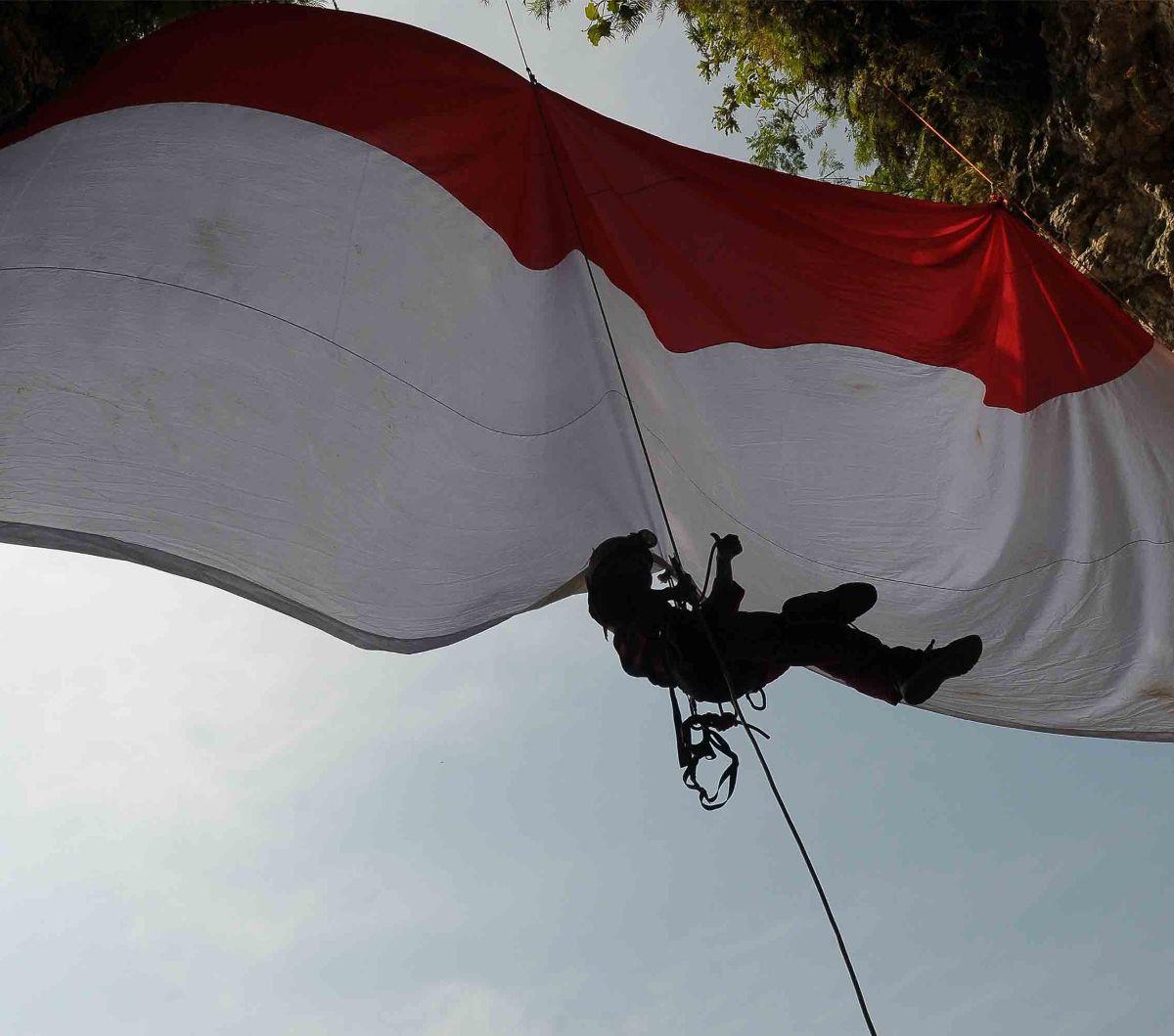 Bendera merah putih yang berukuran besar 6 x 4 meter itu dibentangkan pada mulut goa.