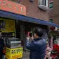 Seorang pria berpose di depan foto sutradara film Bong Joon-ho di restoran pizza bernama 'Sky Pizza' di Seoul, 13 Februari 2020. Lokasi syuting Parasite di Korea Selatan semakin ramai dikunjungi turis setelah film tersebut berhasil memboyong dan mendominasi di penghargaan Oscar 2020. (Ed JONES/AFP)