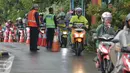 Petugas mengamati pengendara sepeda motor yang masuk menuju tol dalam kota di pintu tol Taman Mini 2, Jakarta, Kamis (21/4). Hujan deras yang mengguyur sejak semalam membuat sejumlah jalan di Ibu Kota tergenang banjir. (Liputan6.com/Angga Yuniar)