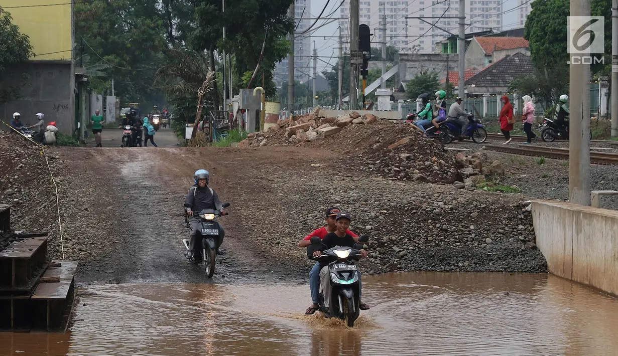 Pengendara motor melintasi genangan air di kawasan Kemiri Muka, Depok, Jawa Barat, Senin (2/10). Buruknya sistem drainase menyebabkan air selalu menggenang setiap musim hujan sehingga mengganggu aktivitas warga. (Liputan6.com/Immanuel Antonius)