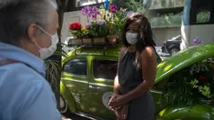 Roberta Machado (kanan) asal Brasil dan pelanggan berbincang di sebelah VW Beetle 1969 miliknya yang diubah menjadi toko bunga keliling di Copacabana, Rio de Janeiro, Rabu (14/10/2020). Perempuan 51 tahun ini mengubah VW kodok untuk bertahan dari krisis akibat pandemi COVID-19. (MAURO PIMENTEL/AFP)