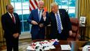 Presiden AS, Donald Trump memegang kartu merah yang diberikan presiden FIFA, Gianni Infantino (tengah) selama pertemuan di Oval Office Gedung Putih, Selasa (28/8). Presiden FIFA bertemu Trump untuk membahas kesiapan Piala Dunia 2026. (AP/Evan Vucci)