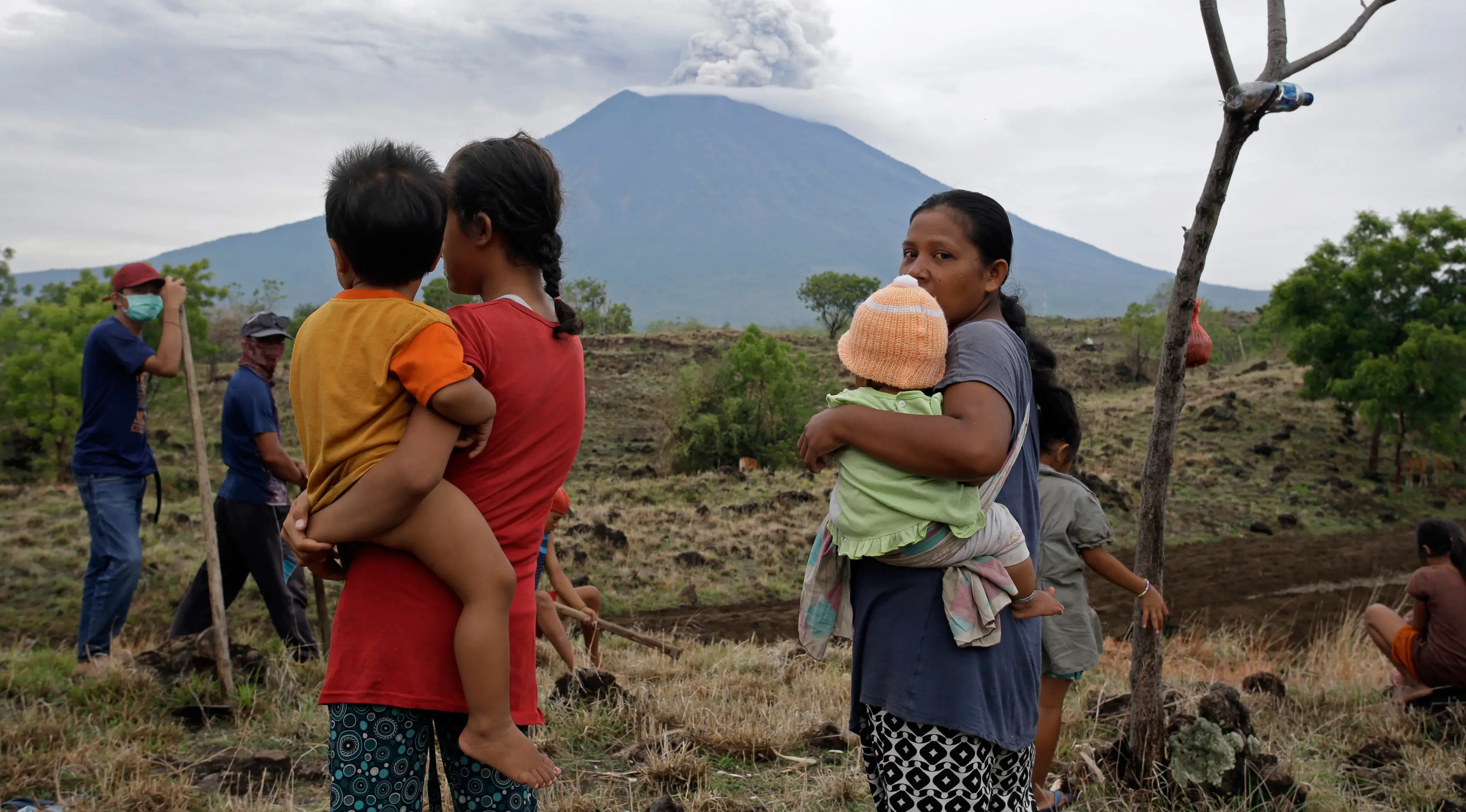 Warga desa melihat Gunung Agung yang mengeluarkan asap dan abu vulkanis dari Karangasem, Bali, Rabu (29/11). Meskipun Gunung Agung terus menunjukkan peningkatan aktivitas vulkanik, sebagian warga memilih tetap beraktivitas. (AP/Firdia Lisnawati)