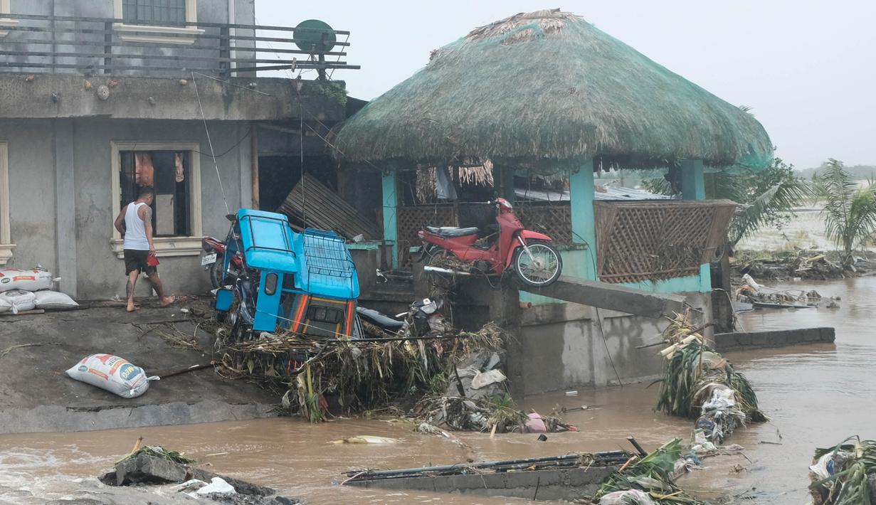 Seorang pria berjalan melewati kerusakan yang disebabkan oleh banjir bandang pada Kamis 24 Oktober 2024 di kota Libon, provinsi Albay, Filipina. (AP Photo/John Michael Magdasoc)