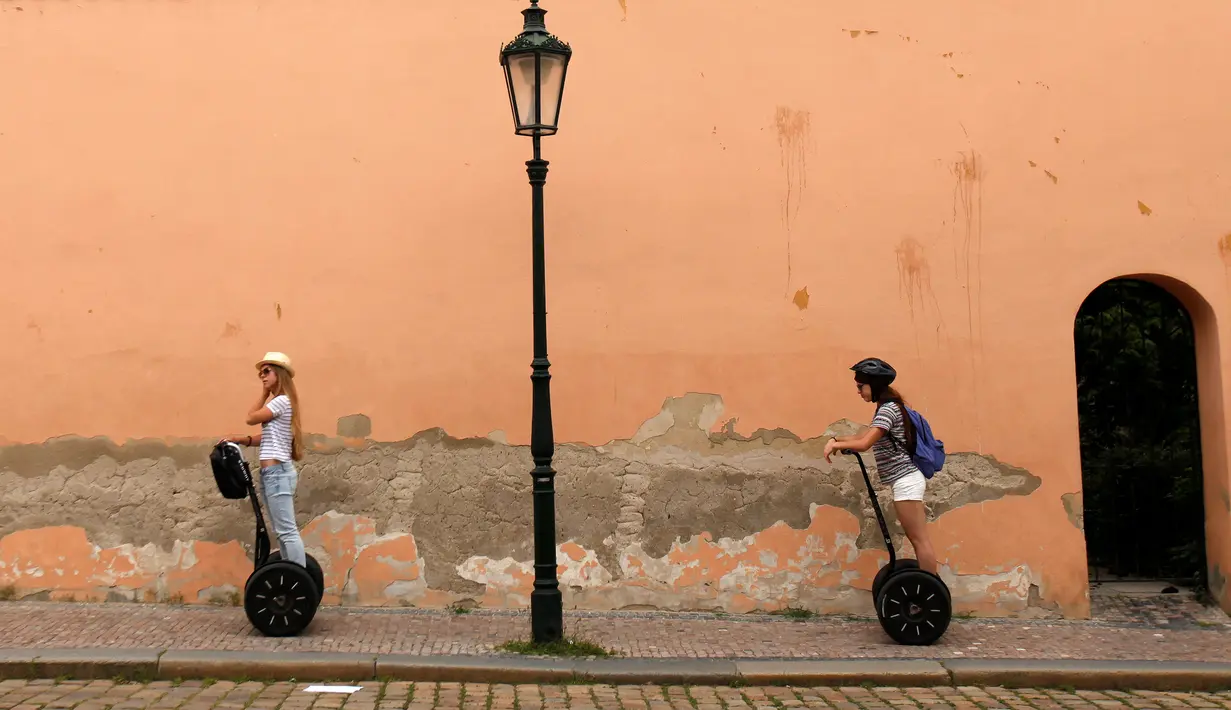 Dua orang turis menggunakan segway untuk berwisata mengelilingi pusat kota Praha, Ceko, Selasa (19/7). Segway adalah kendaraan personal listrik beroda 2 yang mampu menyeimbangkan sendiri. (REUTERS/David W Cerny)