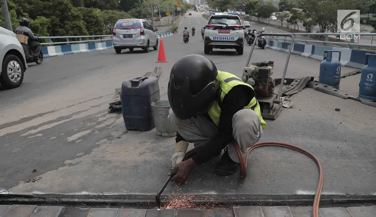 Para pekerja memperbaiki aspal di flyover Kemayoran yang mengalami kerenggangan, Jakarta, Sabtu (5/1). Hal itu disebabkan rusaknya sambungan celah sambungan alias expansion joint. (Merdeka.com/Imam Buhori)