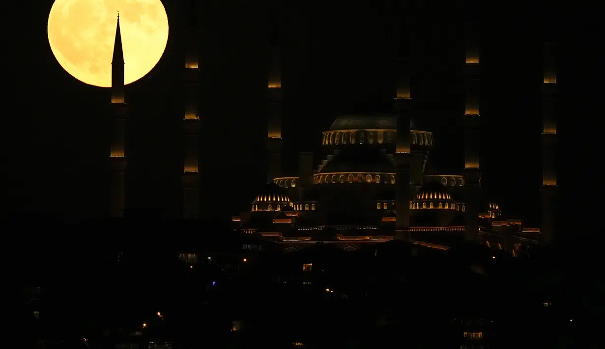 Bulan purnama terbit di belakang masjid Camlica di Istanbul, Turki, Senin (3/7/2023). Bulan purnama penuh yang dijuluki Buck Moon yang muncul pada 3 Juli menjadi supermoon pertama tahun ini. (AP Photo/Francisco Seco)