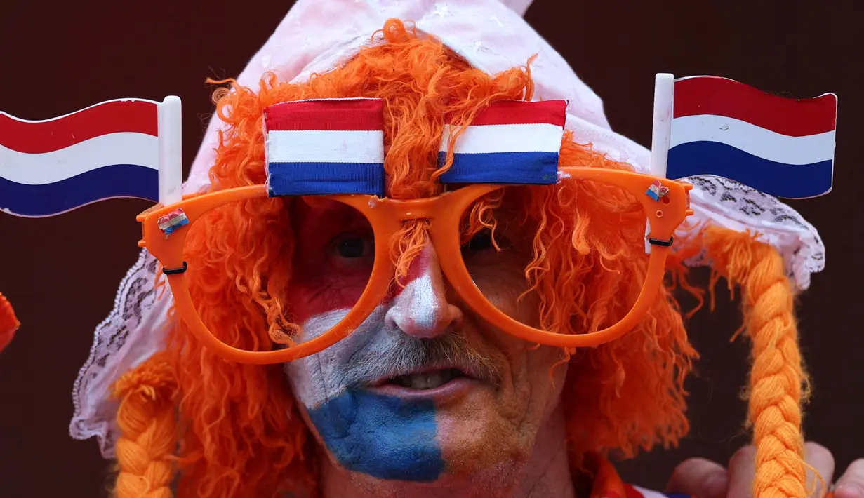Seorang pendukung Belanda berkacamata hitam dan mengenakan bendera Belanda berpose sebelum pertandingan sepak bola Euro 2024 Grup D antara Belanda dan Prancis di Stadion Leipzig, Leipzig, pada 21 Juni 2024. (Adrian DENNIS/AFP)